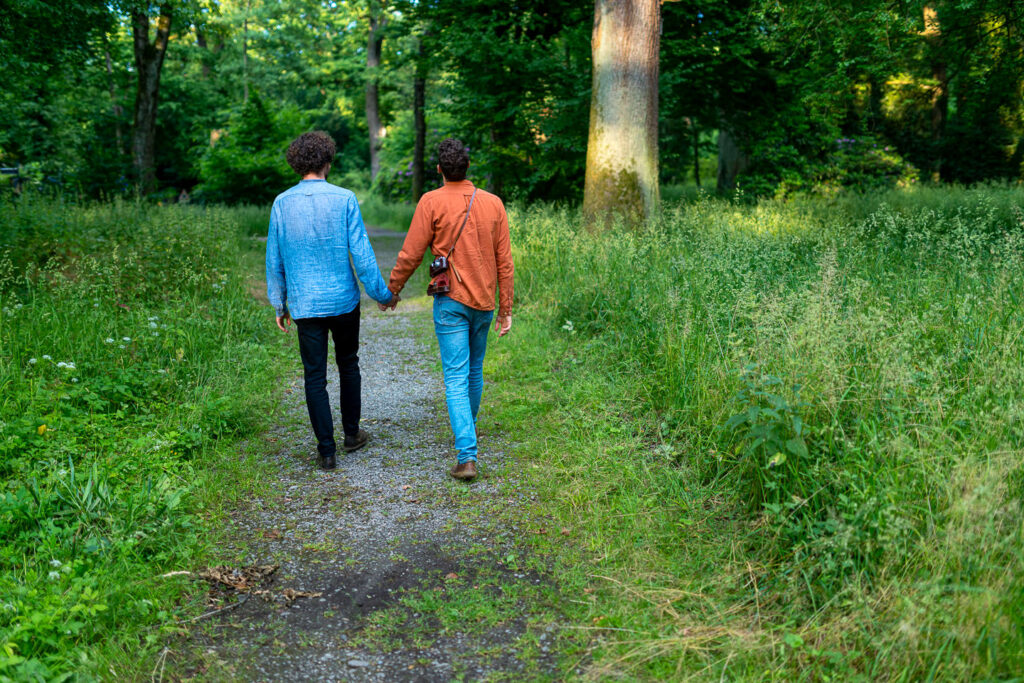 Verlobtes Paar spaziert durch grünen Waldweg bei natürlichem Engagement-Shooting in Freiburg.