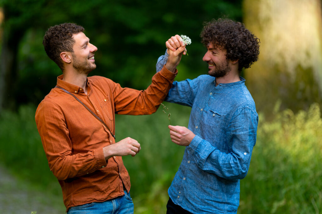 Zwei Männer geben sich High-Five beim Verlobungsshooting in der Natur von Freiburg.