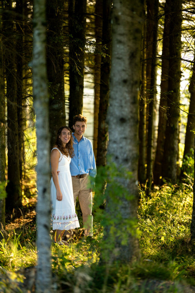 Verliebtes Paar im sonnendurchfluteten Wald während der goldenen Stunde beim romantischen Fotoshooting.