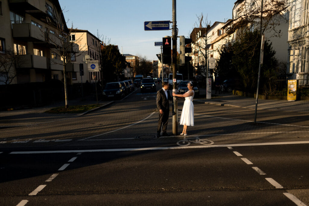 Brautpaar überquert Straße bei goldenem Abendlicht während Engagementshooting in Freiburgs Altstadt.