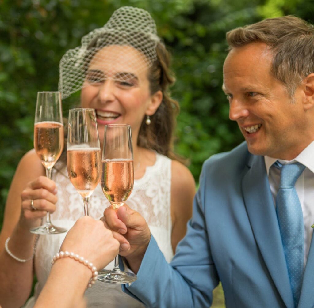 Glückliches Brautpaar stößt mit Champagner im Freien bei ihrer Hochzeit in Konstanz an.