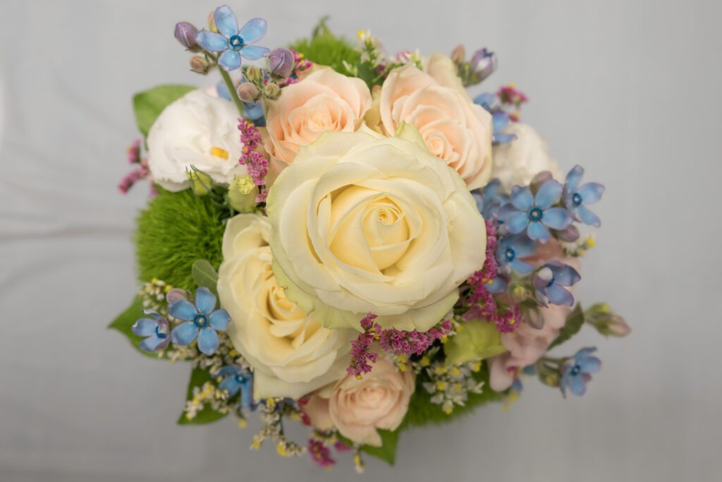 Eleganter Brautstrauß in Creme mit Rosen, blauen Vergissmeinnicht und Lavendel-Akzenten für die Hochzeit.