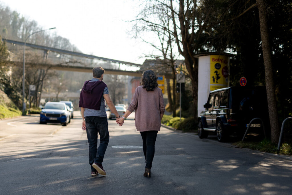 Paar spaziert Hand in Hand unter Brücke beim Engagementshooting in Freiburg am Schlossberg.