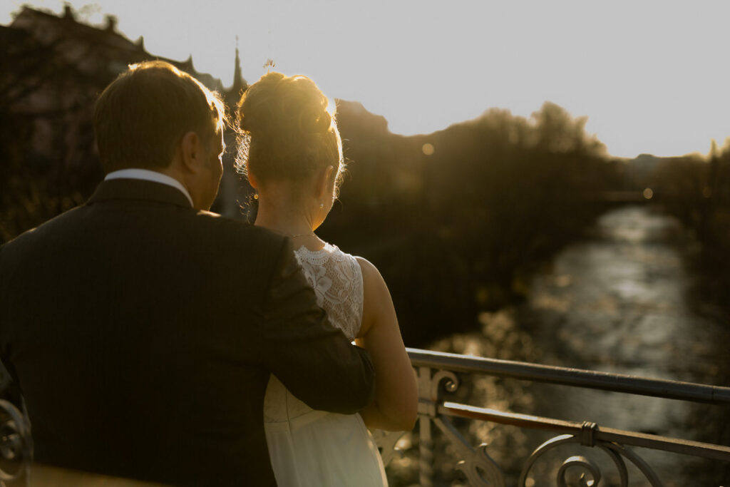 Paar bei romantischem Engagementshooting zur Golden Hour auf Brücke in Freiburg mit Flussblick.