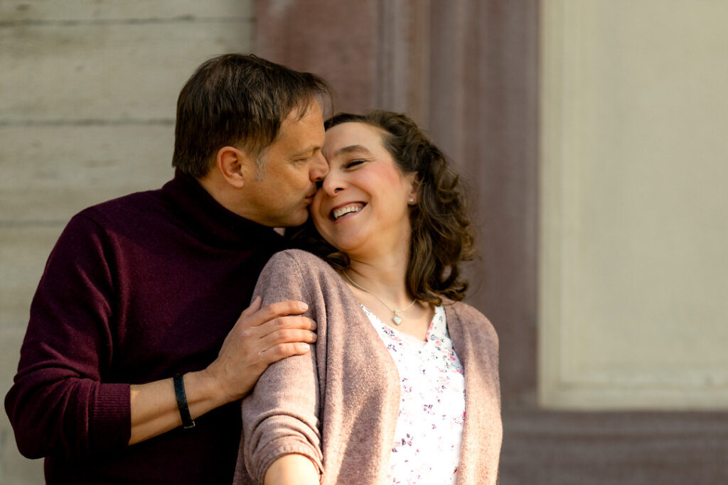 Engagementshooting Freiburg: Verliebtes Paar in zärtlicher Umarmung vor klassischen Säulen am Schlossberg.
