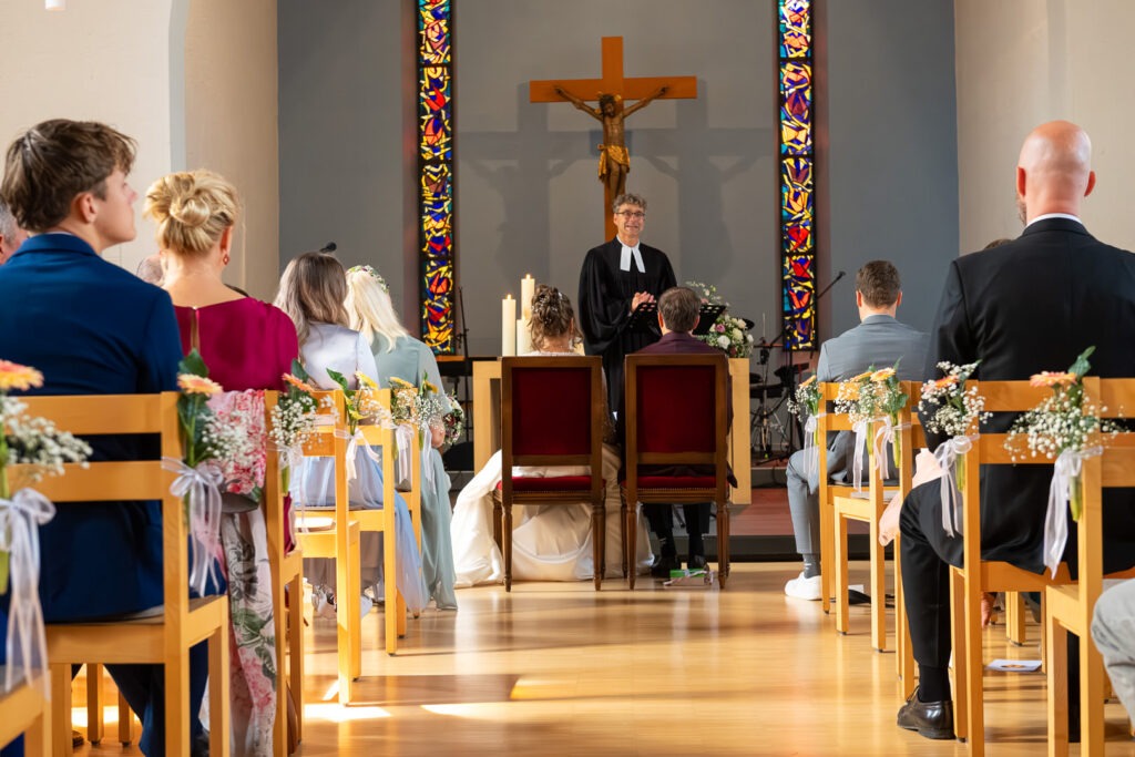 Kirchliche Trauung in moderner Kirche am Bodensee mit Brautpaar vor Altar und Kruzifix.