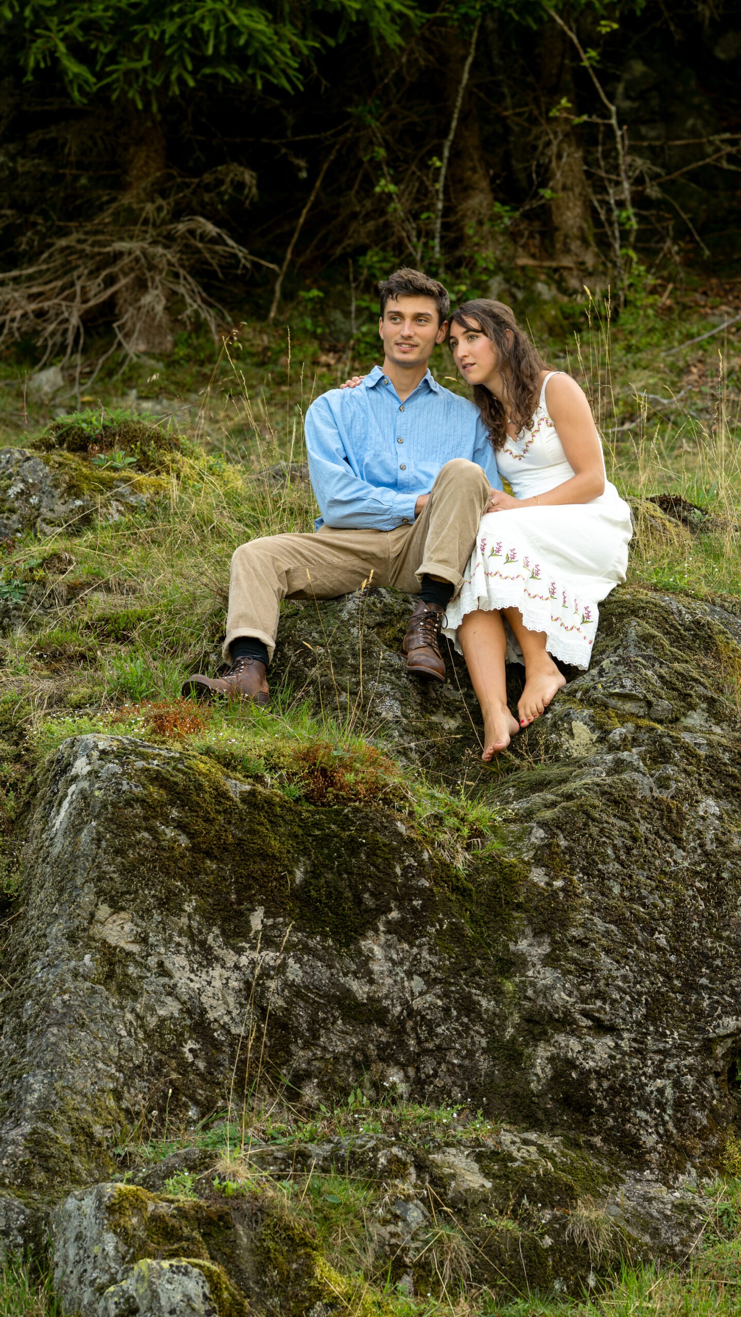 Hochzeit Caro und Vale – das Brautpaar sitzt still auf bemoosten Felsen, sie barfuß, er zugewandt.