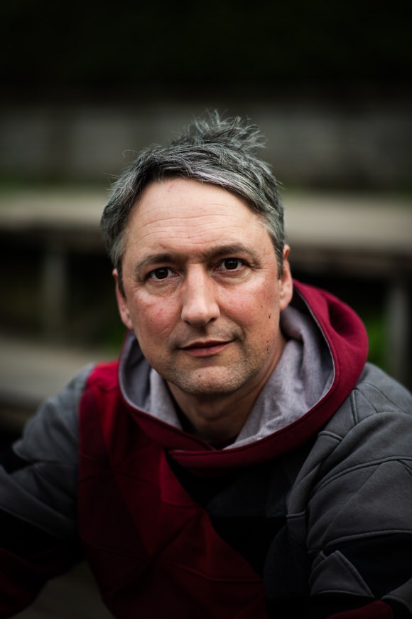 Gregor Marstaller, Hochzeitsfotograf aus Freiburg im Breisgau, in professionellem Portrait mit bordeauxrotem Pullover.