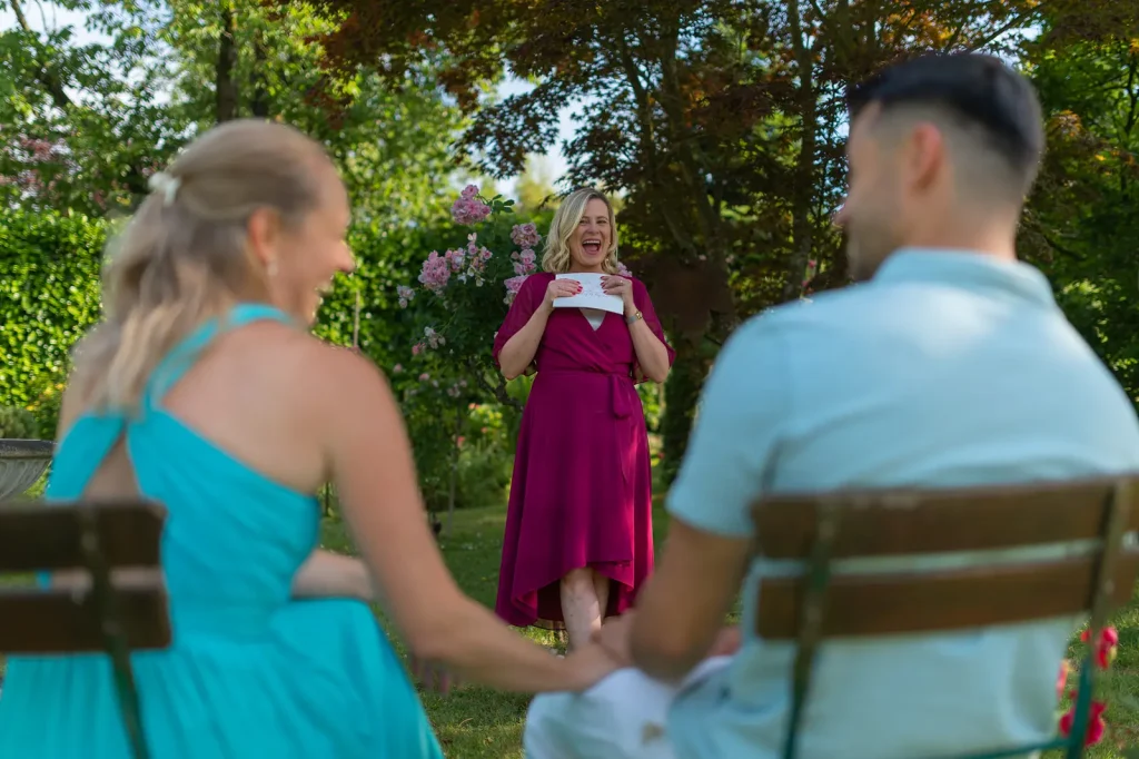 Standesbeamtin lacht laut bei freier Trauung von Svenja und Yannik im Garten.