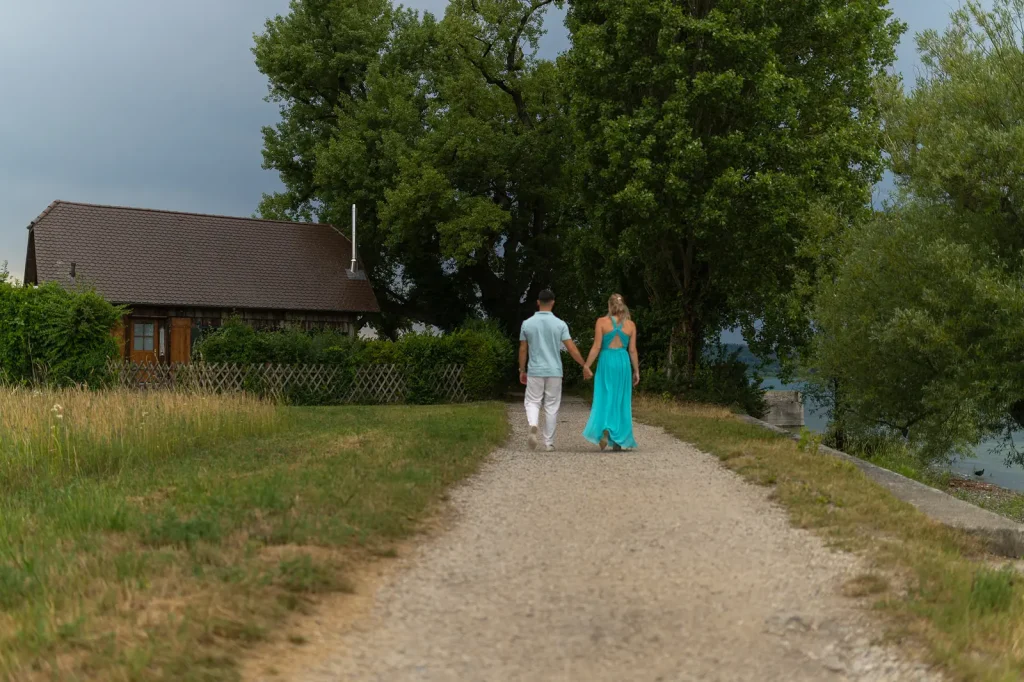 Paar geht Hand in Hand am Bodensee-Ufer entlang.