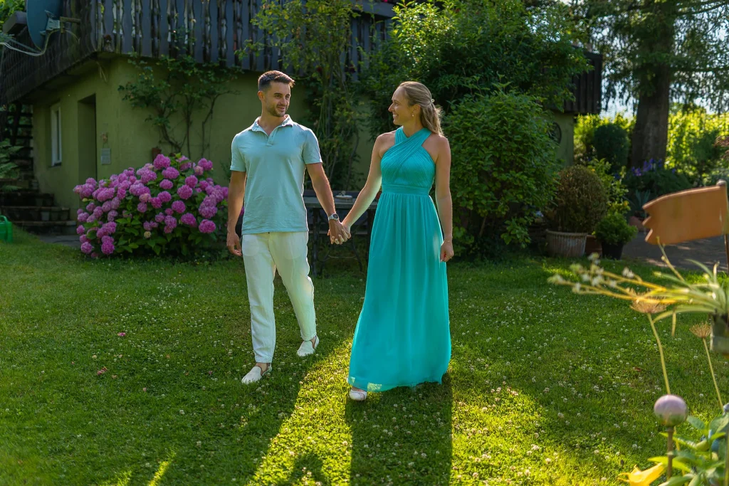 Paar Svenja und Yannik spaziert Hand in Hand durch Garten am Bodensee.