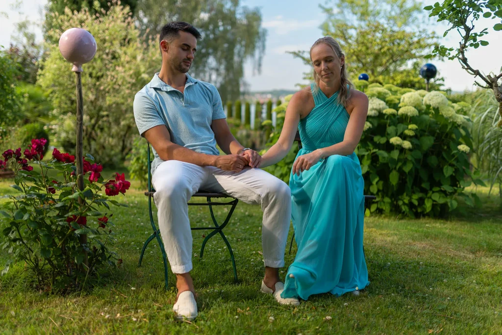 Verlobungsshooting Bodensee – Svenja und Yannik halten Hände im Garten.